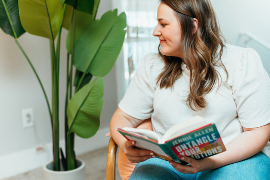Lizzie looking at a plant and holding a book