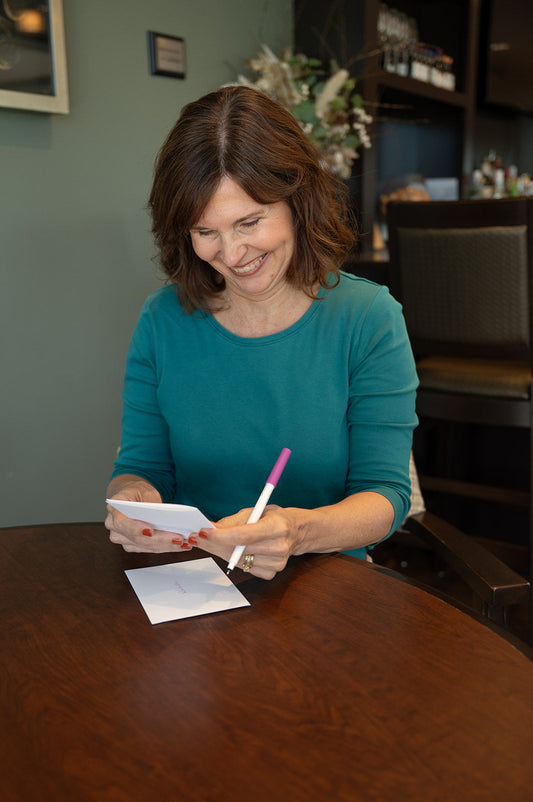 Woman holding a card and a pen smiling