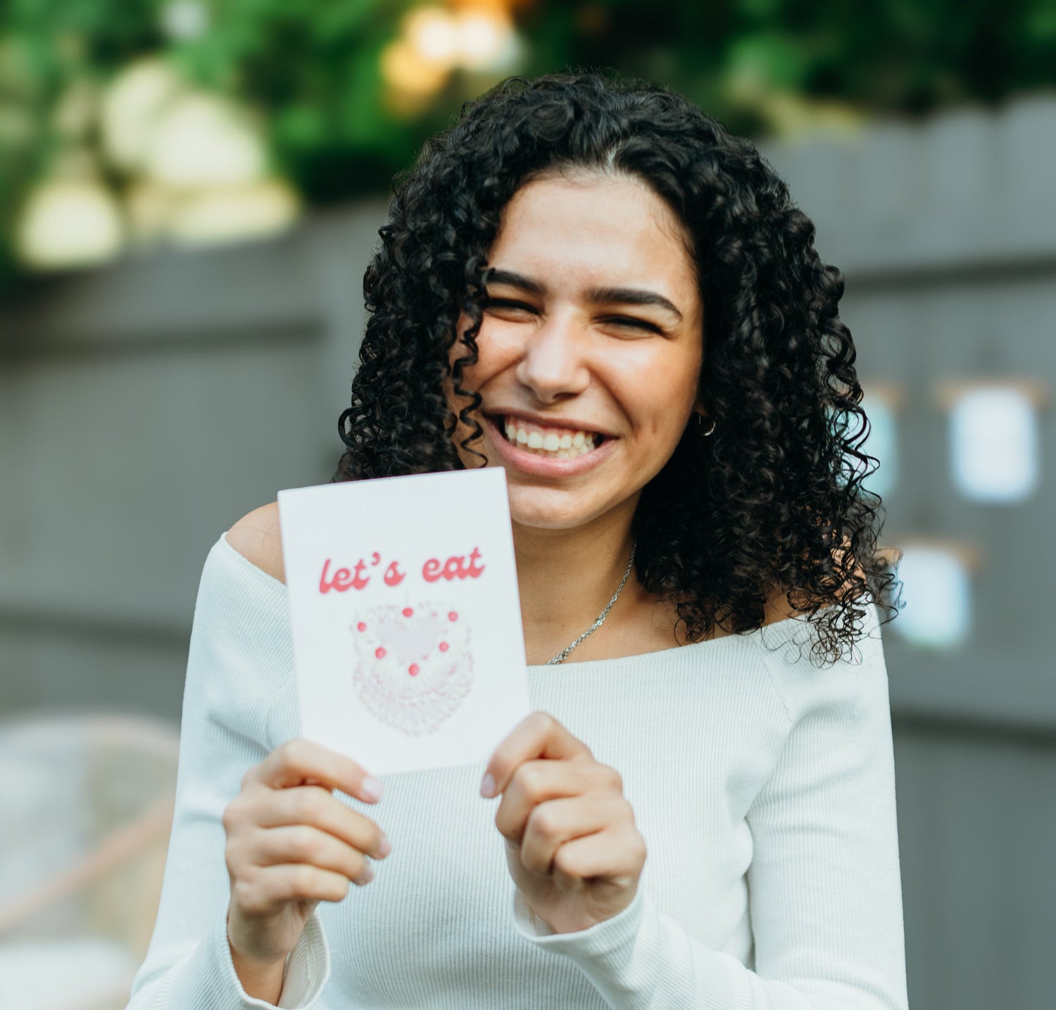girl holding greeting card that says let's eat cake.